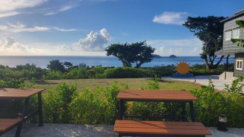 two picnic tables with a view of the ocean at 三仙台日出民宿 in Chenggong
