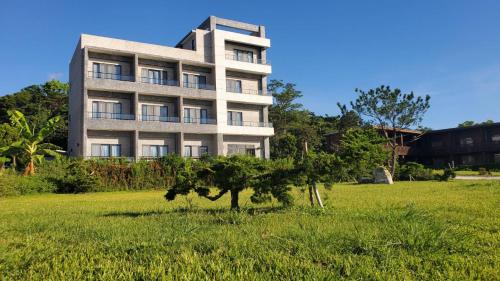 a building in a field with a tree in front of it at 三仙台日出民宿 in Chenggong