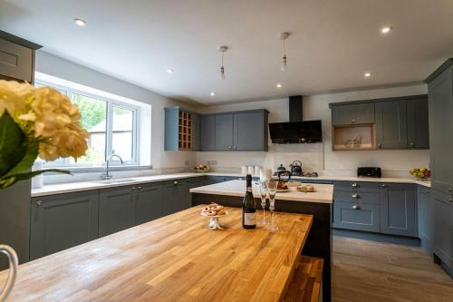 a kitchen with blue cabinets and a wooden table at Throwley, woodland lodge with hot tubs for 14 in Oakamoor