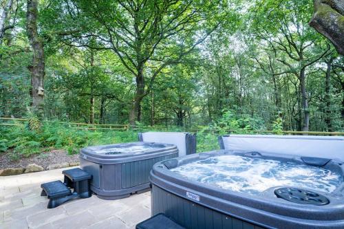 a hot tub sitting on a patio with trees at Throwley, woodland lodge with hot tubs for 14 in Oakamoor