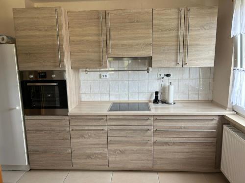 a kitchen with wooden cabinets and a stove top oven at Ferienwohnung Winzenburg Natur nah und ruhig gelegene Ferienwohnung nah am Steinhuder Meer und Dinopark Münchehagen in Rehburg-Loccum