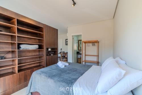 a bedroom with a large bed with wooden shelves at Studio Charmoso apenas 200m da Praia - PMO0404 in Florianópolis