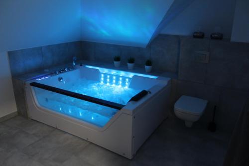 a bath tub with a blue light in a bathroom at Villa Bella Zastan Sauna & Jacuzzi in Międzywodzie