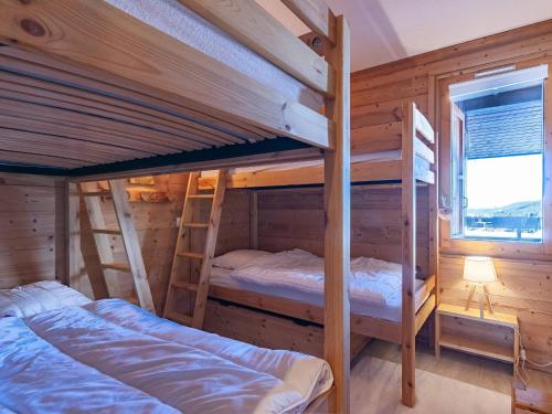 Cette chambre en bois dispose de 2 lits superposés et d'une fenêtre. dans l'établissement Charmant duplex rénové 8 pers, balcon sud, Méribel - FR-1-355-236, à Les Allues
