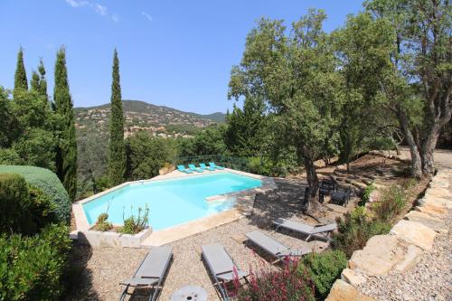 une piscine dans un jardin avec des chaises et des arbres dans l'établissement Villa Dolce pour 8 personnes avec piscine privée à La Londe-Les-Maures, à La Londe-les-Maures