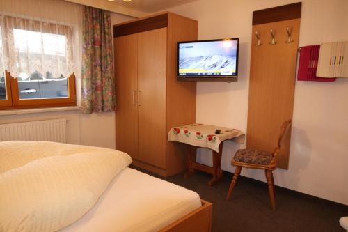 a bedroom with a bed and a tv on the wall at Ferienwohnung im Zentrum von Kappl Paznauntal PAZN100 by FeWo-PLAN in Kappl
