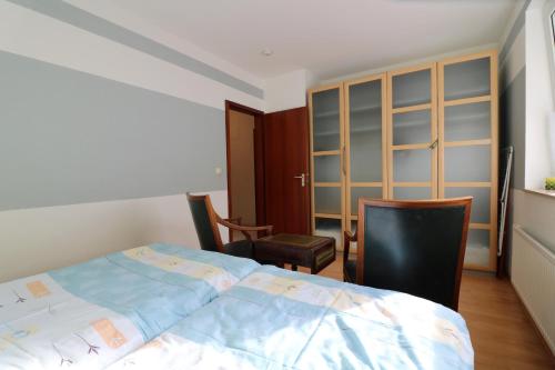 a bedroom with a bed and two chairs and a cabinet at Ferienwohnung Schenefelder Drift in Stadt Schenefeld