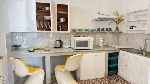a kitchen with a counter with two chairs and a microwave at Mykonos Seaview Nests - Tourlos Getaways in Tourlos