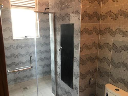 une douche avec une porte vitrée dans une salle de bain dans l'établissement Vista Luxury Apartment, à Kigali