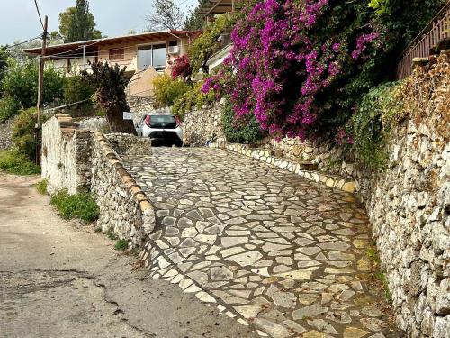a stone road next to a stone wall with purple flowers at Hoolit House in Vournikás