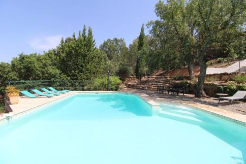 une grande piscine avec des chaises longues et des arbres dans l'établissement Villa Dolce pour 8 personnes avec piscine privée à La Londe-Les-Maures, à La Londe-les-Maures
