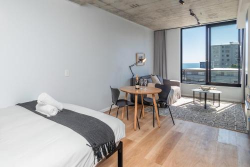 een slaapkamer met een bed en een tafel met stoelen bij Cosy Oasis in the heart of Sea Point in Kaapstad