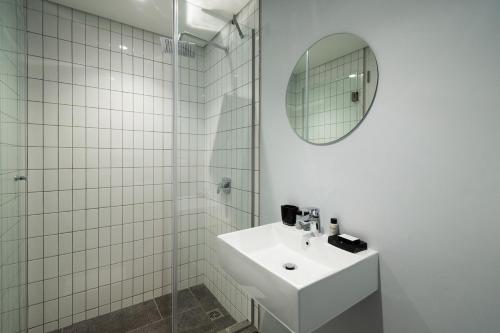 een witte badkamer met een wastafel en een spiegel bij Cosy Oasis in the heart of Sea Point in Kaapstad