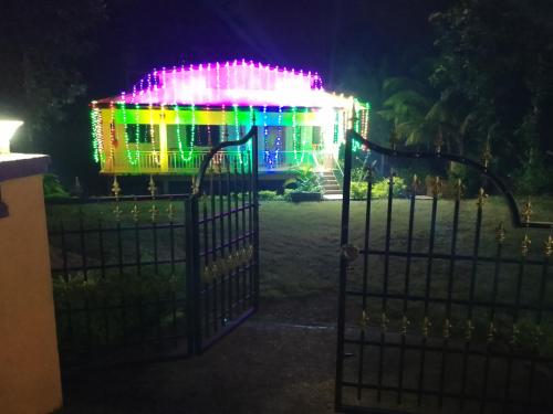 a gate with a building covered in christmas lights at Parvati Narayan Guest House in Sānikatta