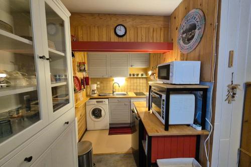 a small kitchen with a microwave and a sink at Appartement idéal famille - pied des pistes in Les Déserts