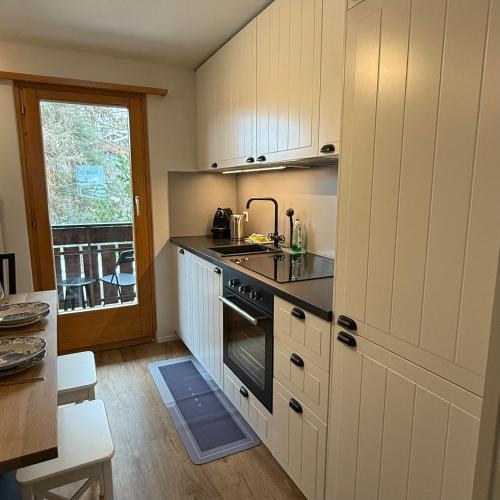a kitchen with white cabinets and a stove top oven at Chalet Apt Melesez in Zermatt
