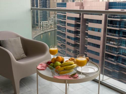 a table with a bowl of fruit and two glasses of orange juice at Bel appartement Dubai marina in Dubai