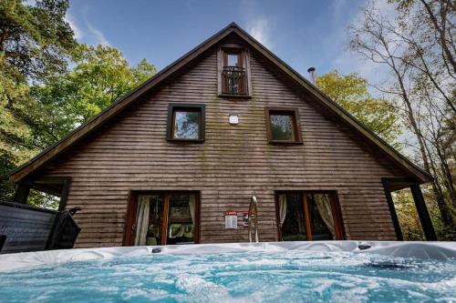 a house with a large pool in front of it at Stanton, woodland lodge with hot tub for 14 in Oakamoor