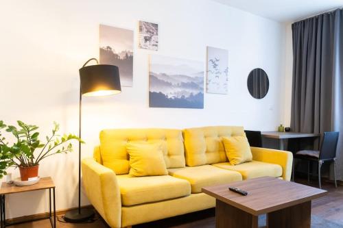 a yellow couch in a living room with a table at Elegant Studio in the Heart of Brno in Brno