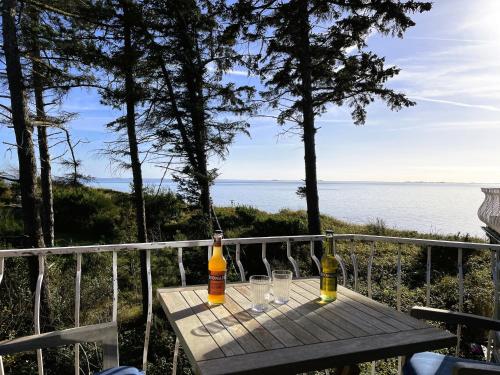 a wooden table with two bottles and glasses on a balcony at Huus Lüttenblick Whg Halligenblick in Wyk auf Föhr