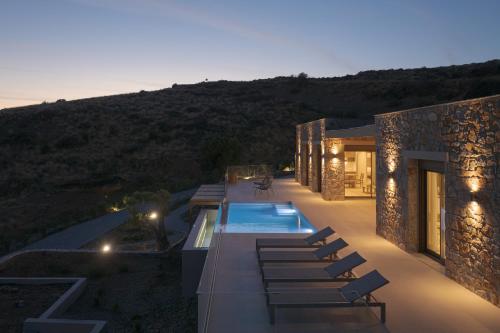 a house with a swimming pool and lounge chairs at VK Villas - Votsalo & Kyma Villas, By ThinkVilla in Léntas