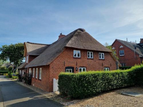 a red brick house with a thatched roof at Hüs Lorenzen in Oevenum