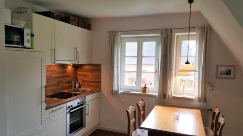 a kitchen with a table and a sink and a window at Heimathafen in Wyk auf Föhr