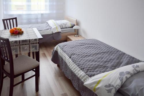 a bedroom with two beds and a table with a bowl of fruit at Apartament Szczecin Pomorzany in Szczecin