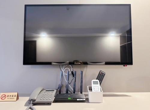 a flat screen tv on top of a desk with a phone at Miloft Suvarnabhumi Airport Hotel in Bangkok