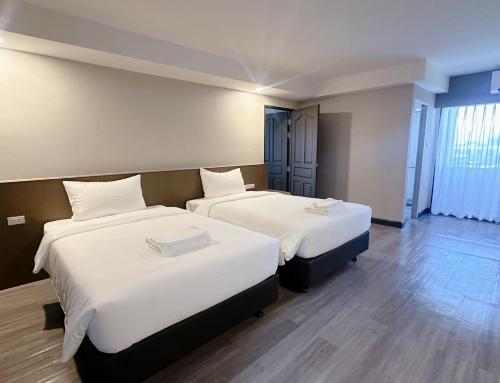 two beds in a hotel room with white sheets at Miloft Suvarnabhumi Airport Hotel in Bangkok