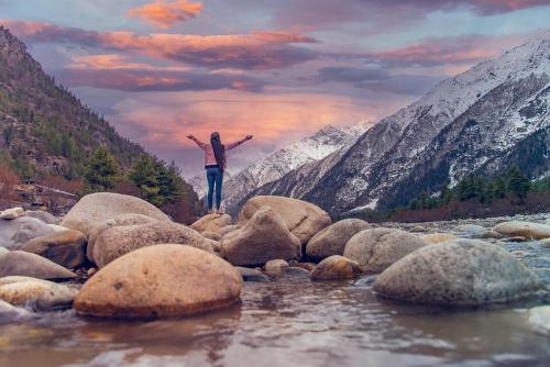 a person standing on rocks in a river at Kinnor Retreat in Sāngla