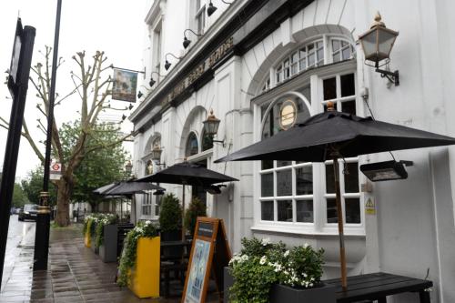 a building with two umbrellas on a city street at PubLove @ The White Ferry, Victoria in London
