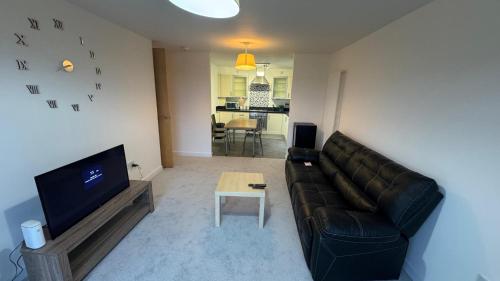 a living room with a black leather couch and a table at The Metro Oasis in Edinburgh