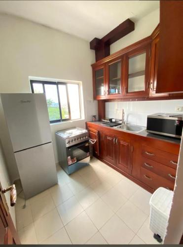 a kitchen with a white refrigerator and wooden cabinets at BH Lurury in Yaoundé