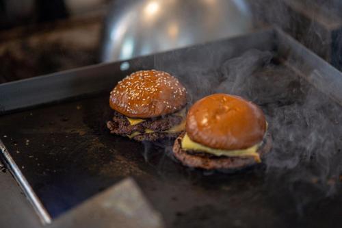 two hamburgers are cooking on a grill at PubLove @ The Crown, Battersea in London