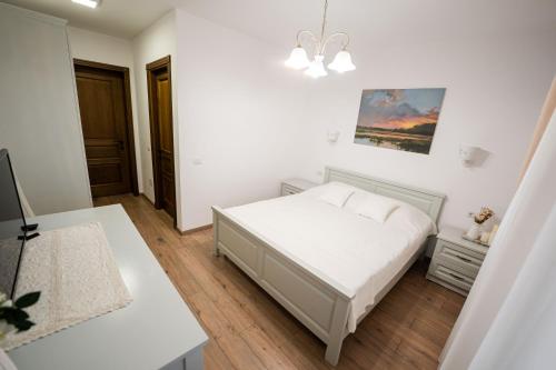 a white bedroom with a bed and a table at Casa Andra in Siret