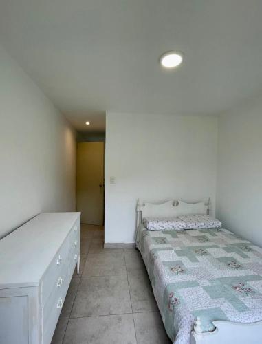 a white bedroom with a bed and a dresser at Casa Tullpa in Aspitia