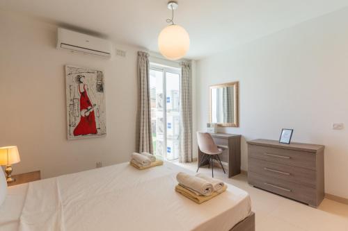 Is-SwieqiLarge apartment with pool的一间卧室，配有一张床、一张书桌和一扇窗户