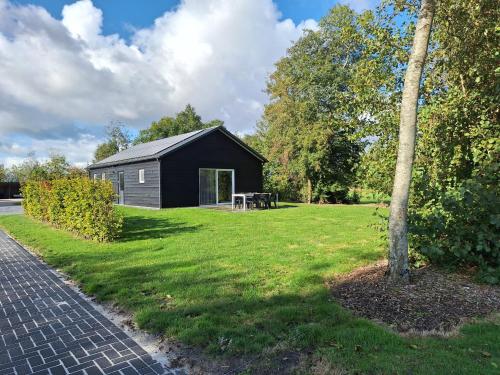 a black house with a picnic table in a yard at Het vrije uitzicht Giethoorn in Giethoorn