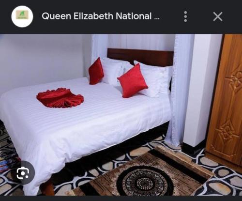 a bed with red pillows on it in a room at QUEEN ELIZABETH CULTURE CENTRE kasese in Kasese