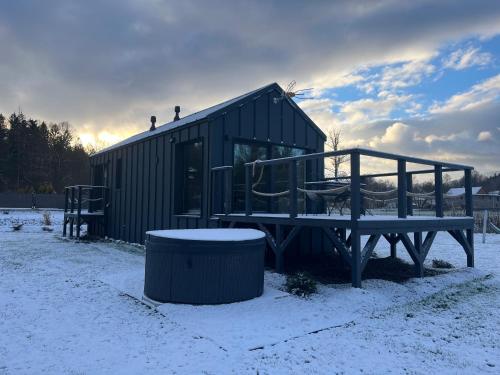 a shed with a picnic table and a bench in the snow at Holiday Hill Karpnki, Sauna, Domek Hygge-balia, Domek Lagom-jacuzzi in Karpniki