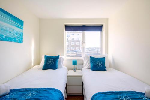 two twin beds in a room with a window at 2BR Apartment with Balcony on Brighton Marina in Brighton & Hove