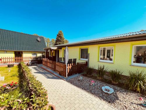 a yellow house with a fence and a patio at FEWO Am Haussee Feldberger Seenlandschaft in Feldberg