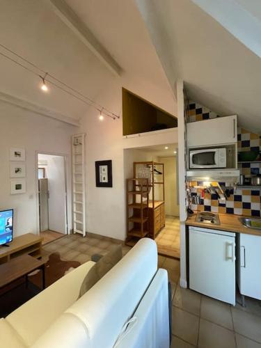 un salon avec un canapé blanc et une cuisine dans l'établissement Cosy appartement place des Abbesses-Sacré-Cœur !, à Paris