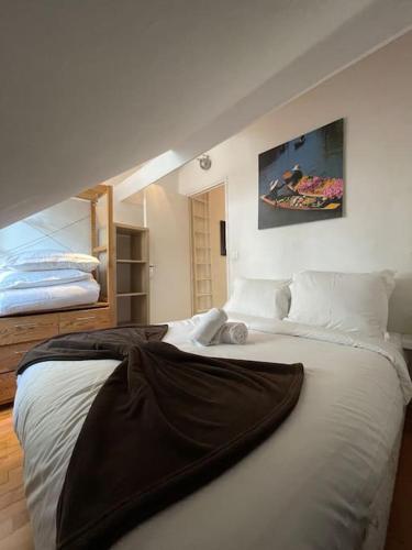 - une chambre avec un grand lit blanc et une couverture dans l'établissement Cosy appartement place des Abbesses-Sacré-Cœur !, à Paris