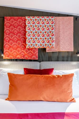 a bed with red pillows and towels hanging on a wall at Maison Boissière BARNES Residences in Paris