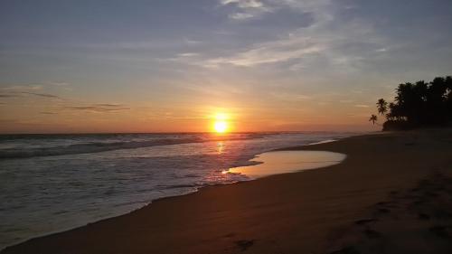 a sunset on a beach with the ocean at Lilly House in Unawatuna