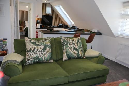 a green couch with pillows on it in a living room at THE HIDEAWAY - LUXURY SELF CATERING COASTAL APARTMENT with PRIVATE ENTRANCE & KEY BOX ENTRY JUST A FEW MINUTES WALK TO THE BEACH, SOLENT WAY WALK, SHOPS and many EATERIES & BARS - FREE OFF ROAD PARKING,FULL KITCHEN, LOUNGE,BEDROOM , BATHROOM & WI-FI in Lymington
