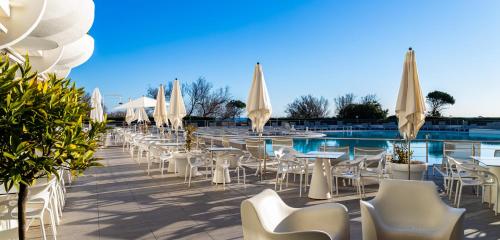 a row of tables and chairs next to a pool at Hôtel Les Corallines - Thalasso & Resort in La Grande-Motte