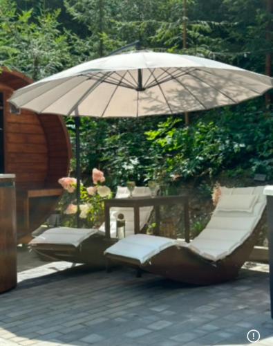 a group of lounge chairs under an umbrella at Modrzewiowy Zakątek in Desznica
